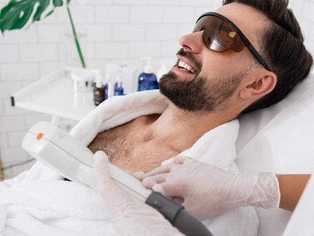 bearded man sitting in laser safety goggles in spa salon 1