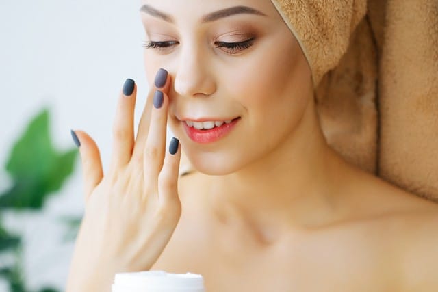 Happy Smiling Young Woman Holds Cream for Face