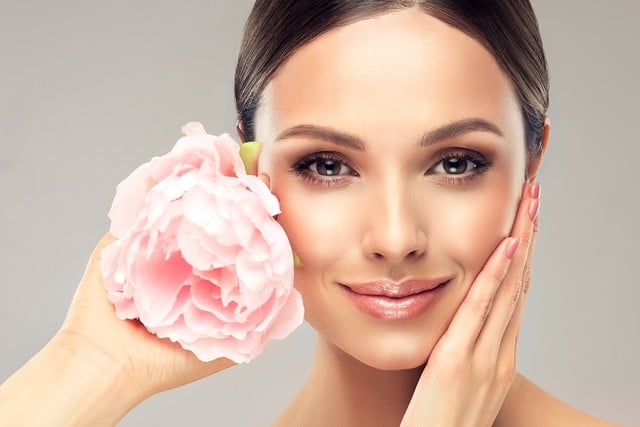 Beautiful young woman with delicate peony flower.